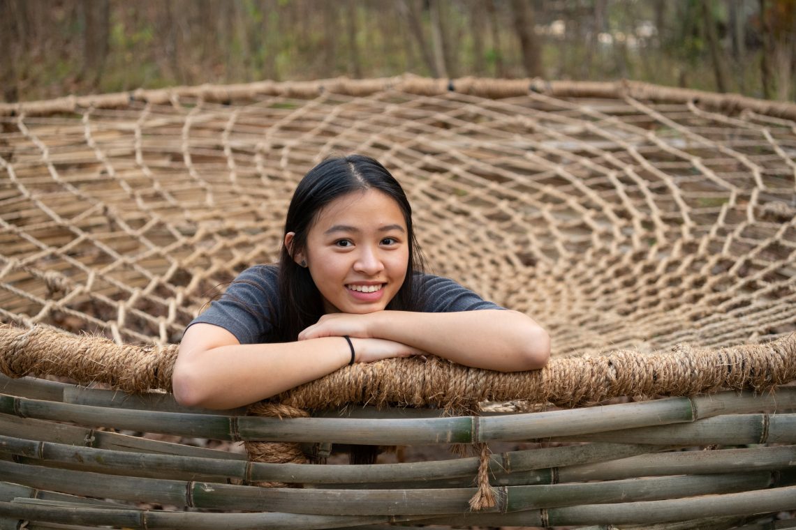 Reggie Zhao '21 relaxes on the sculpture she built behind Wilson Hall.